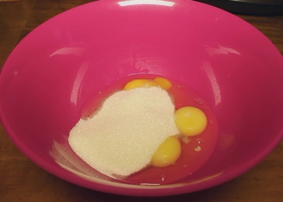 В глубокую чашку разбиваем яйца, высыпаем сахар и взбиваем миксером до увеличения массы в три раза
